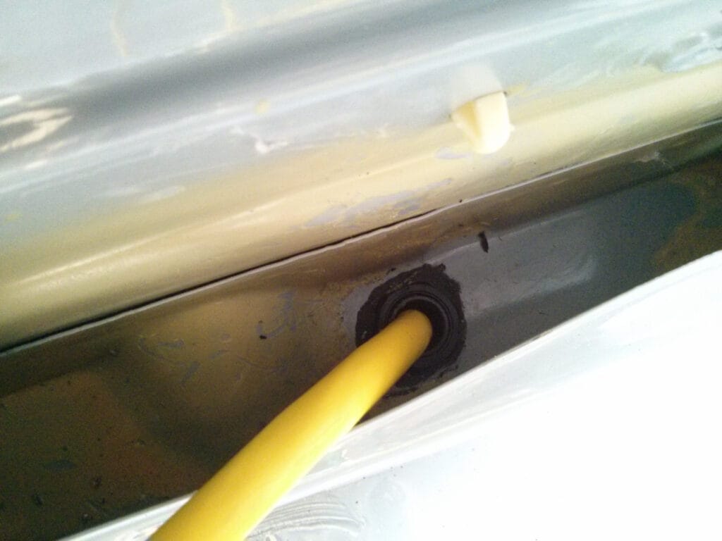The grommet mounted in the floor inside a wall recess at the back of the van