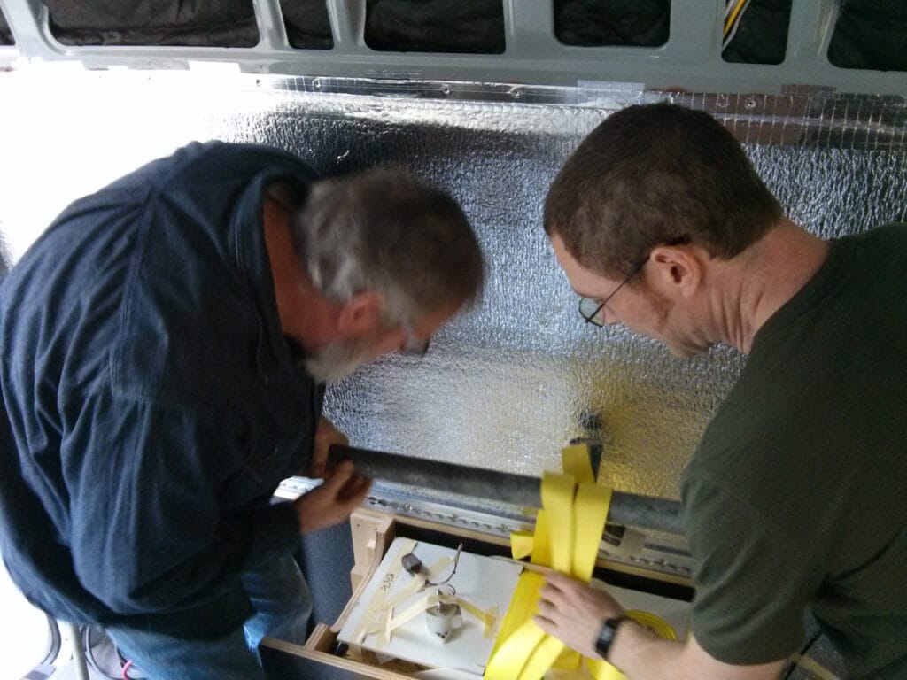 Two people can lift this battery into place. Notice there's a wooden cover over the terminals in case we drop something metal on to them.