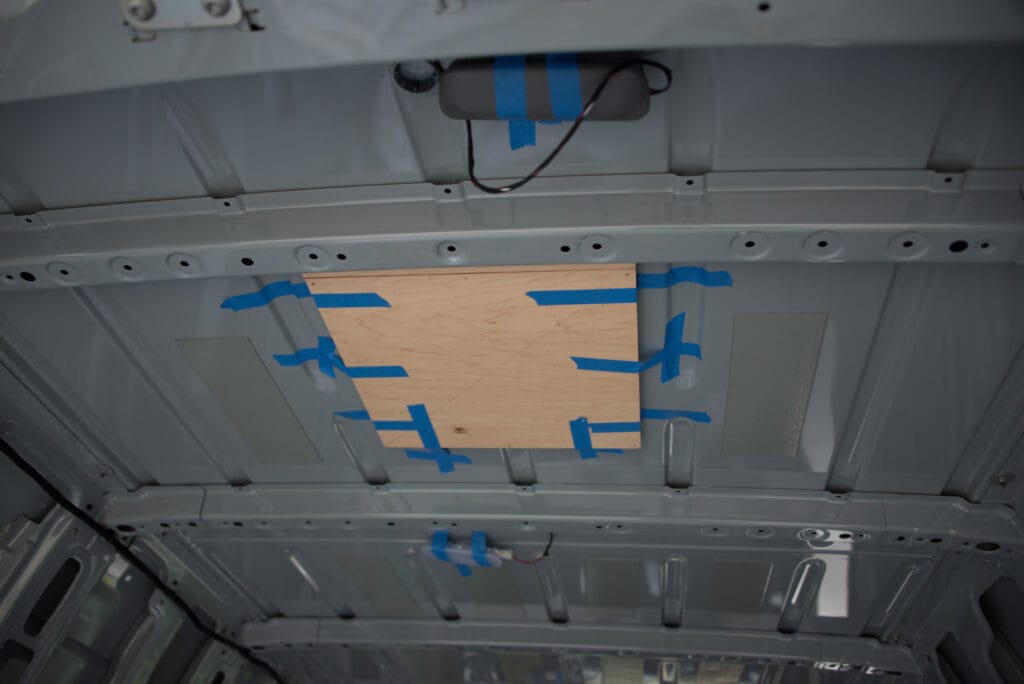Wooden template in place ready to drill holes through to the outside of the roof. First holes through the van!
