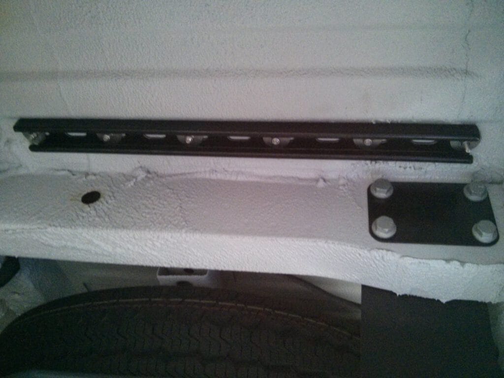 Unistrut channel under the van, with stainless bolts and fender washers coming from the l-track inside