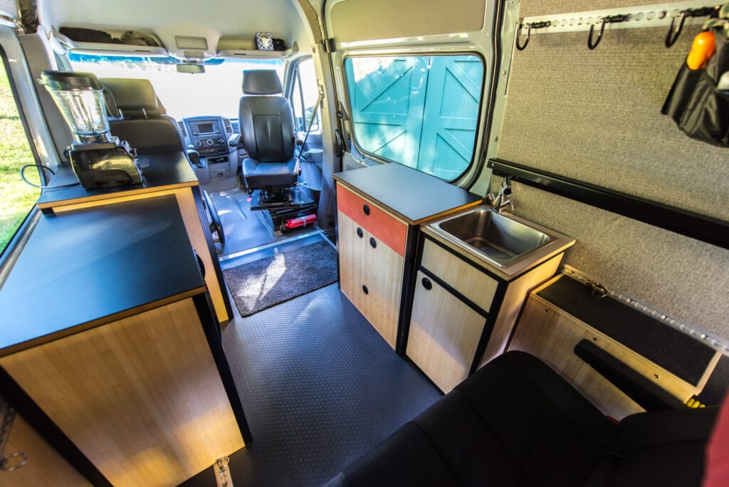 Living area of the van - bench seat moved to third passenger position to make space for cabinetry. Swivel on passenger seat