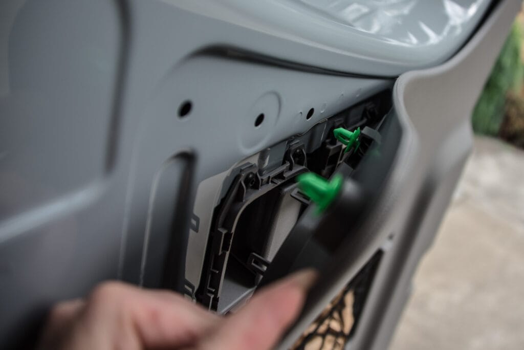 Once you've removed the trim, the rest of this rear panel is just like the other door panels. Use a trim tool to pry the green clips out from their holes.