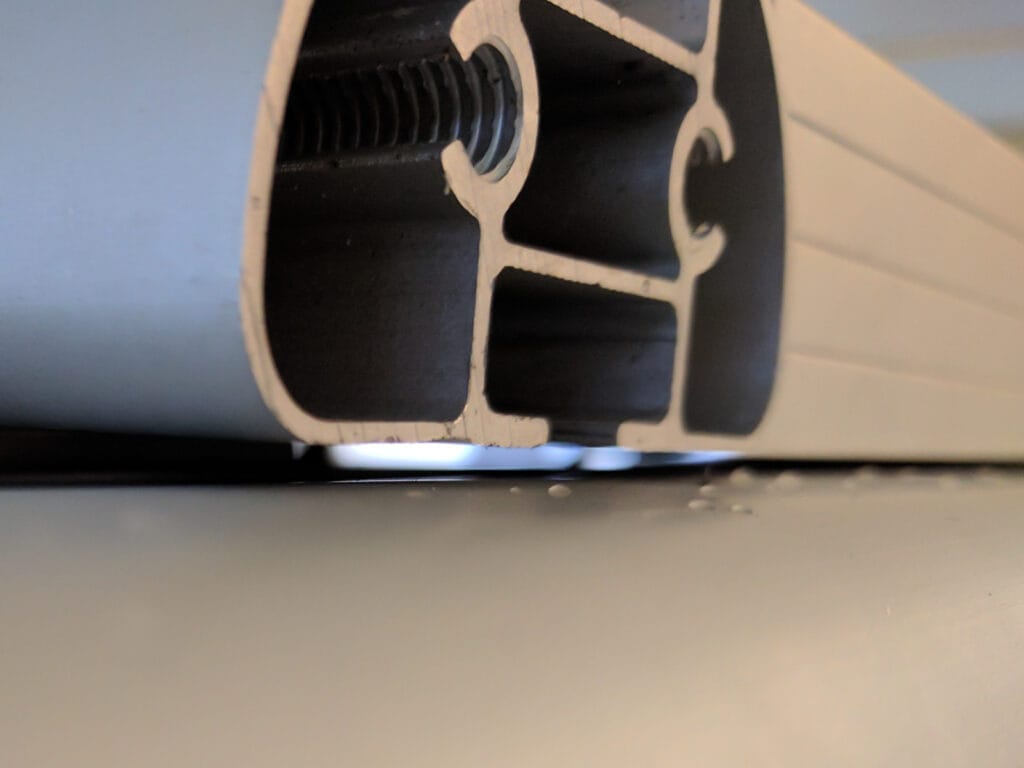 The top of the awning is about 3/32" below the base of the rack and solar panels