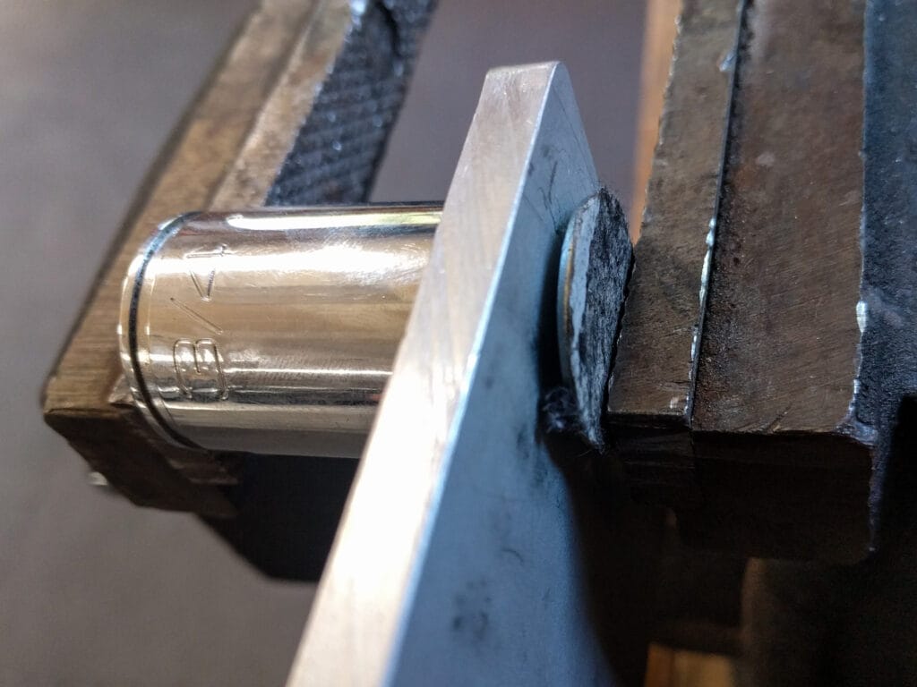 Clamp the elevator bolt and socket in a vice or tap with a hammer to set the bolt