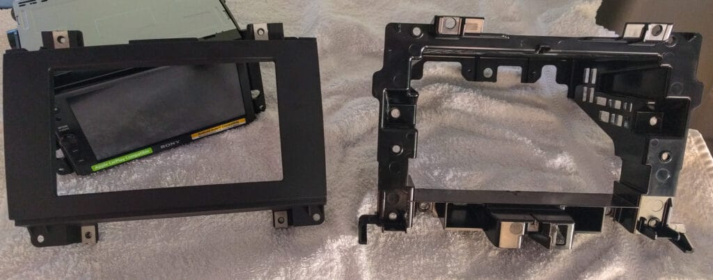 The "factory radio delete" piece of plastic that we had to remove (right) and the Scosche fascia panel (left)