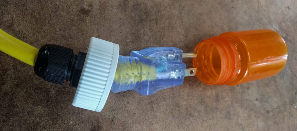 The "ideal" solution to keeping the plug ends clean - a cable gland through a bottle lid, so the bottle could screw on over the plug end.
